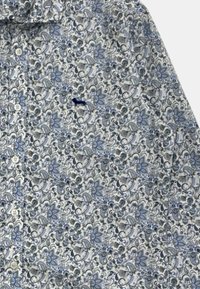 Camicia bianca con motivo floreale blu, caratterizzata da una chiusura a bottoni e un piccolo logo ricamato sul petto. Tessuto di cotone testurizzato.
