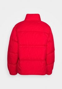 Rød pufferjakke med høj krave, der har et quiltet design og elastiske manchetter. Glat tekstur med en let blank finish.