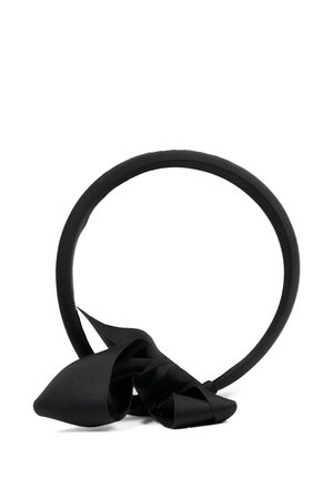 Bandeau noir rembourré avec un grand nœud en satin attaché à la base, présenté sur un fond blanc.