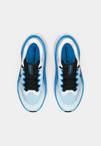 Baskets bleues et blanches avec une tige en mesh, des lacets noirs et une semelle rembourrée, affichant un design élégant et un logo Nike sur la languette.