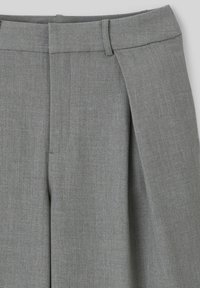 Pantalons plissés gris en tissu doux et texturé, avec une taille propre et des plis marqués à l'avant, adaptés aux looks sur mesure.