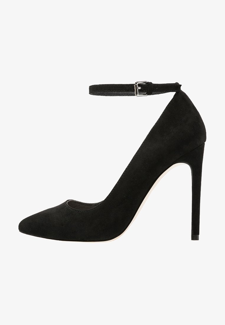 Chaussure à talon haut en daim noir avec un bout pointu, une bride à la cheville et un talon stiletto mince. La tige présente une texture lisse et une finition polie.
