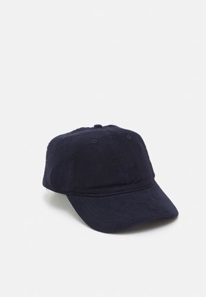 Casquette de baseball en velours côtelé bleu marine foncé avec une couronne à six panneaux et une visière incurvée, présentée sur un fond gris neutre.