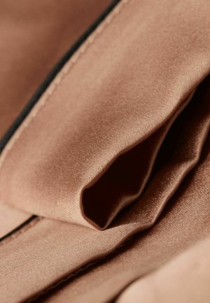 Satinstof in een zachte blushkleur, met een gladde textuur en subtiele glans, met gevouwde lagen en een contrasterend zwart naaddetail.