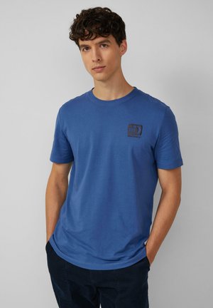 Blaues kurzärmliges T-Shirt aus weichem Baumwollmaterial mit kleinem schwarzem Logo im Bereich der linken Brust. Rundhalsauschnitt und lockere Passform.