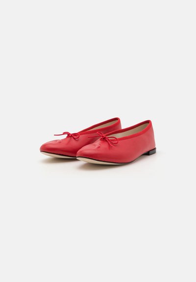 Red leather ballet flats with rounded toes, small bows on the front, and a low, flat black heel. Smooth texture and minimalist design.