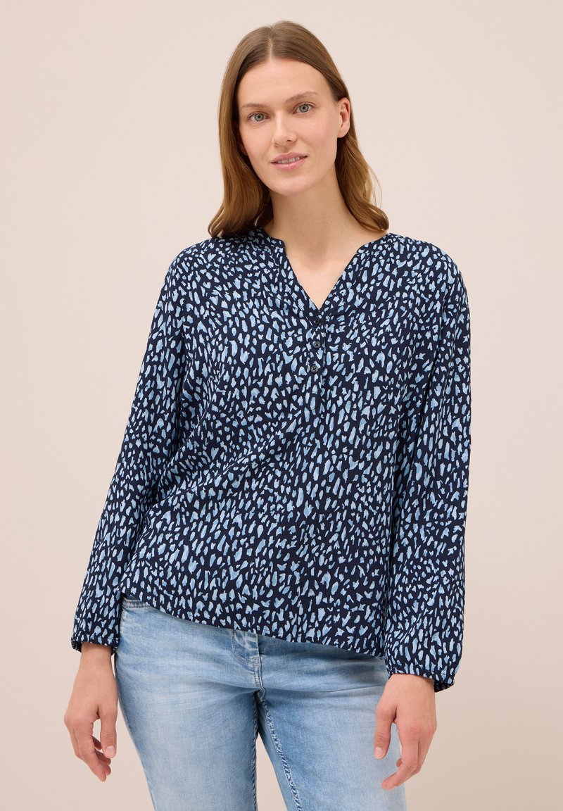 Blusa de color navy con un patrón abstracto en azul claro, con escote en V y mangas largas con puños elásticos. Tejido de mezcla de algodón.