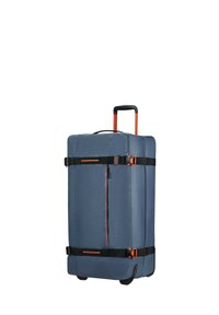 Stort blått tygresväska med svarta remmar, orange detaljer, utdragbar handtag och hjul. Har en sidoficka med dragkedja för förvaring.