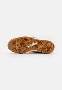 Shoe features a rubber outsole with a textured grip pattern, white and orange upper with colorful accents, and a round logo detail.