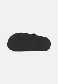 Black rubber sandal sole with a textured, diamond-patterned grip. Rounded shape with a slight upward curve at the toe area.