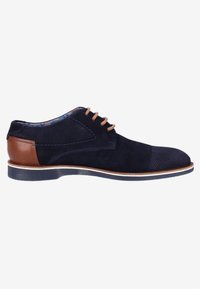 Chaussure de ville pour homme en daim bleu marine avec des lacets marron clair, des détails perforés et un accent en cuir marron au talon sur une semelle plate.