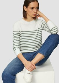 Gestreifter Pullover in Weiß und Olivgrün, mit Rundhalsausschnitt und langen Ärmeln. Getragen mit blauen Jeans und weißen Sneakers.