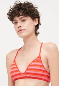 Driehoekige bikini top in rood en roze strepen; gemaakt van textuurstof met dunne bandjes en een diepe V-halsontwerp.