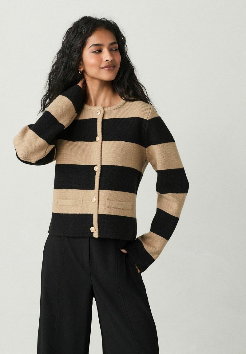 Cardigan lavorato a maglia con strisce orizzontali alternate in nero e beige, scollatura rotonda, bottoni frontali e due tasche anteriori.