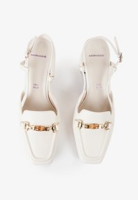 Zapatos slingback de cuero blanco con puntera cuadrada, que presentan detalles en hardware dorado y un diseño de tacón medio. Nombre de la marca impreso en el interior.