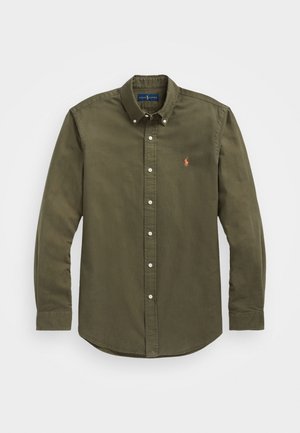 Długa oliwkowa koszula na guziki z kołnierzykiem na guziki i małym czerwonym haftowanym logo na lewej piersi.