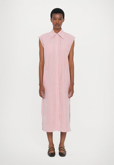 Robe sans manches à rayures rouges et blanches, midi avec un col pointu et des fentes latérales. Le mannequin porte des sandales à brides noires.