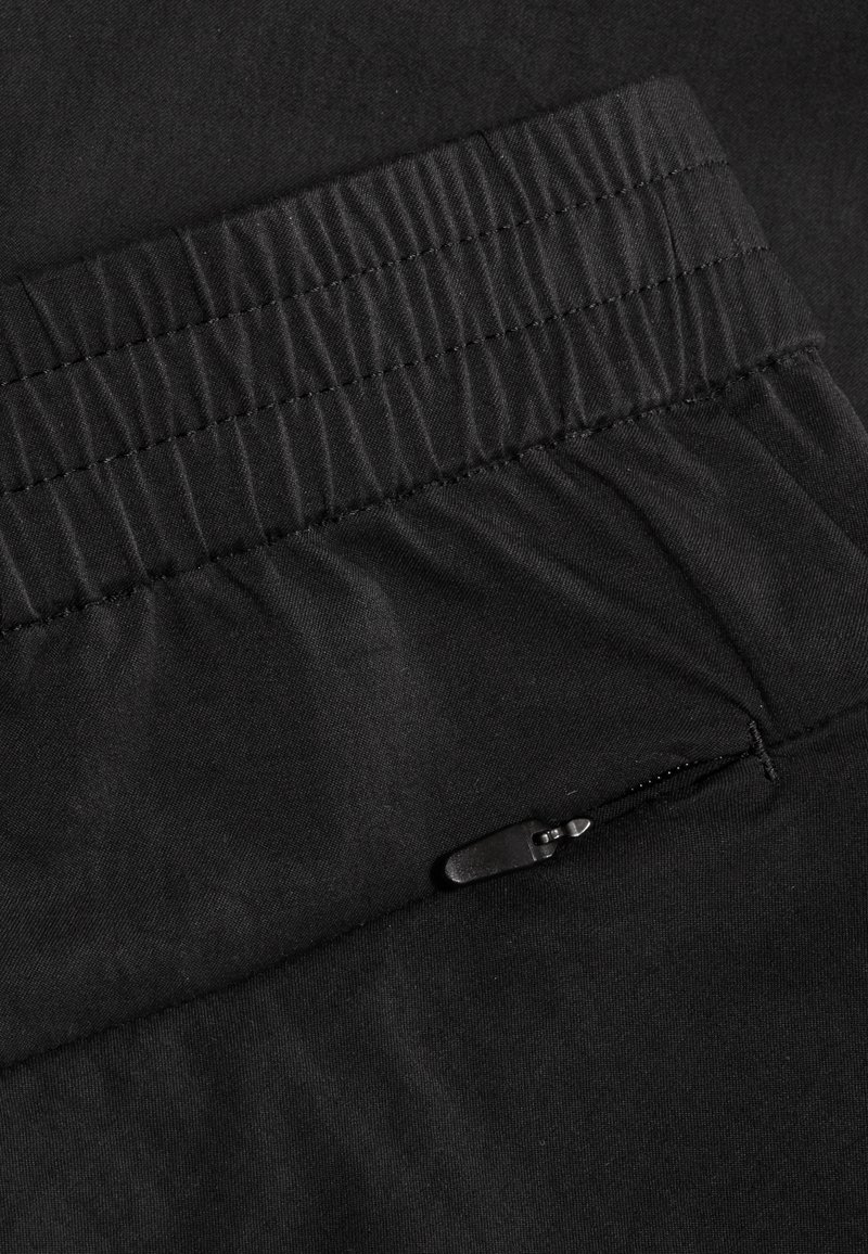 Czarna elastyczna talia z detalami w szwie i czarną kieszenią na zamek błyskawiczny na czarnej tkaninie.