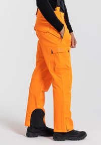Ljust orange cargobyxor med svarta detaljer, med sidofickor, förstärkta nederdelar och justerbara midjeband.