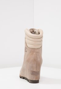 Stivaletti alla caviglia in suede beige con colletto imbottito, tacco a zeppa, superficie testurizzata e suola in gomma con pattern di aderenza.