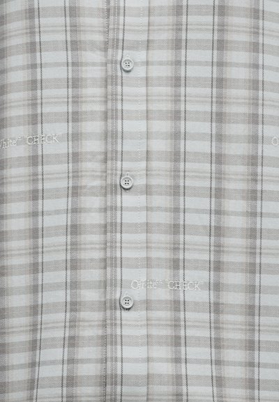 Ανοιχτό γκρι καρό πουκάμισο με κάθετη λωρίδα κουμπιών και λευκό κεντητό κείμενο "Quiet Chuck" διασκορπισμένο στο ύφασμα.