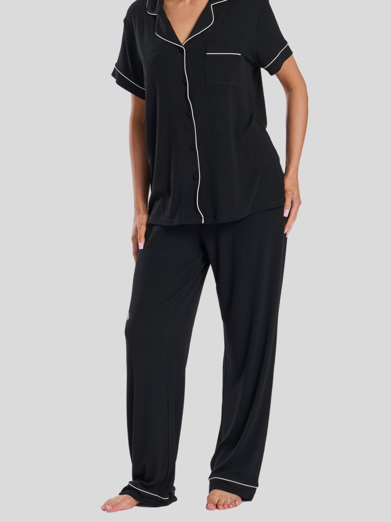 Svart pyjamasset med kortärmad knapp-up topp och långa byxor. Kontrasterande vit piping längs kanterna. Mjukt tyg med avslappnad passform.