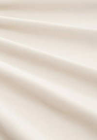 Tejido de color crema con una textura suave, que presenta suaves pliegues y un ligero brillo, adecuado para diversas aplicaciones.