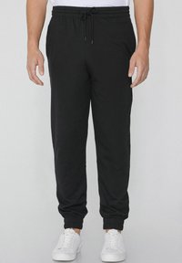 Zwarte sweatpants van zacht katoen met een elastische tailleband en verstelbaar trekkoord. Met cuffs aan de onderkant en zijzakken voor extra gemak.