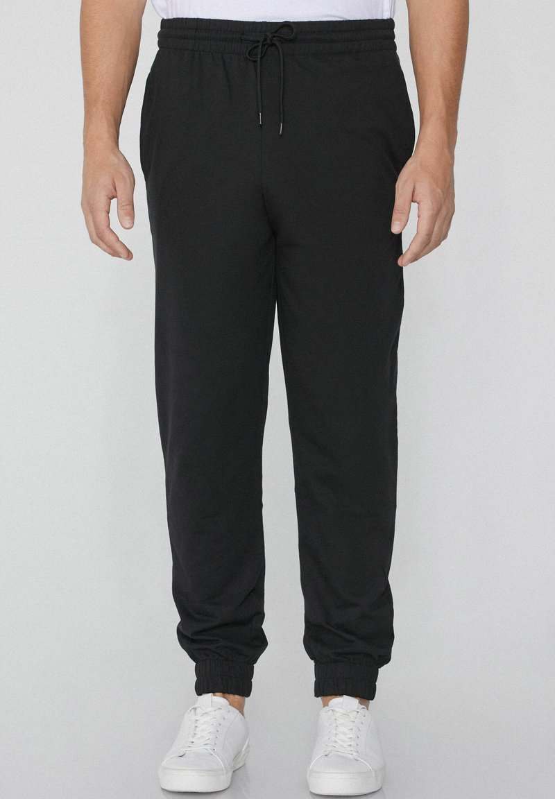 Zwarte sweatpants van zacht katoen met een elastische tailleband en verstelbaar trekkoord. Met cuffs aan de onderkant en zijzakken voor extra gemak.