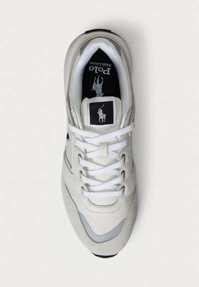 Balts Polo Ralph Lauren apavu sneakers ar saites aizdari, sieta un zamša paneļiem, kā arī zīmola logo uz mēlītes un iekšējās zoles.