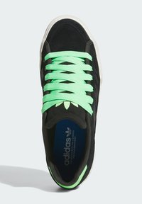 Černé tenisky s semišovým povrchem, které mají jasně zelené šněrování, bílé podešve a modrou stélku se značkováním. Zaoblená špička a nízký design.