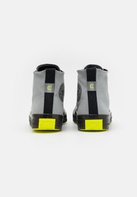 Szare sneakersy wysokie z czarnym paskiem, okrągłym noskiem, żółtymi podeszwami i akcentami logo na pięcie i boku. Materiał kanwasowy.
