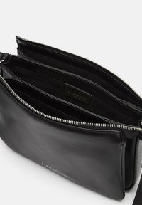 Borsa tracolla in pelle nera con due scomparti principali con zip e tracolla regolabile. Interno con foderina in tessuto ed etichetta.