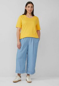 Yellow short-sleeve T-shirt paired with light blue, wide-leg pants. Casual style featuring a relaxed fit and soft fabric. White sneakers complete the look.