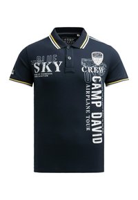 Navy polo shirt featuring a collared design, short sleeves, white and yellow accent stripes, and multiple printed graphics and texts.