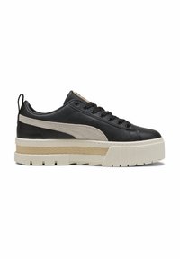 Sneaker in pelle nera con accenti beige, suola bianca spessa, intersuola testurizzata e design con lacci, dotato di una linguetta posteriore per facilitare la calzata.