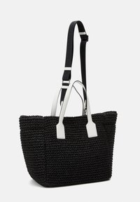 Svart vävd totebag med vita läderhandtag och detaljer. Har en rektangulär form och en avtagbar svart rem med logotypdetalj.