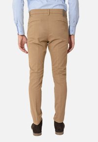 Chinos color marrone chiaro, design slim-fit, in materiale di cotone, con due tasche posteriori, dettagli di cucitura sottili, abbinati a calzature marrone scuro.