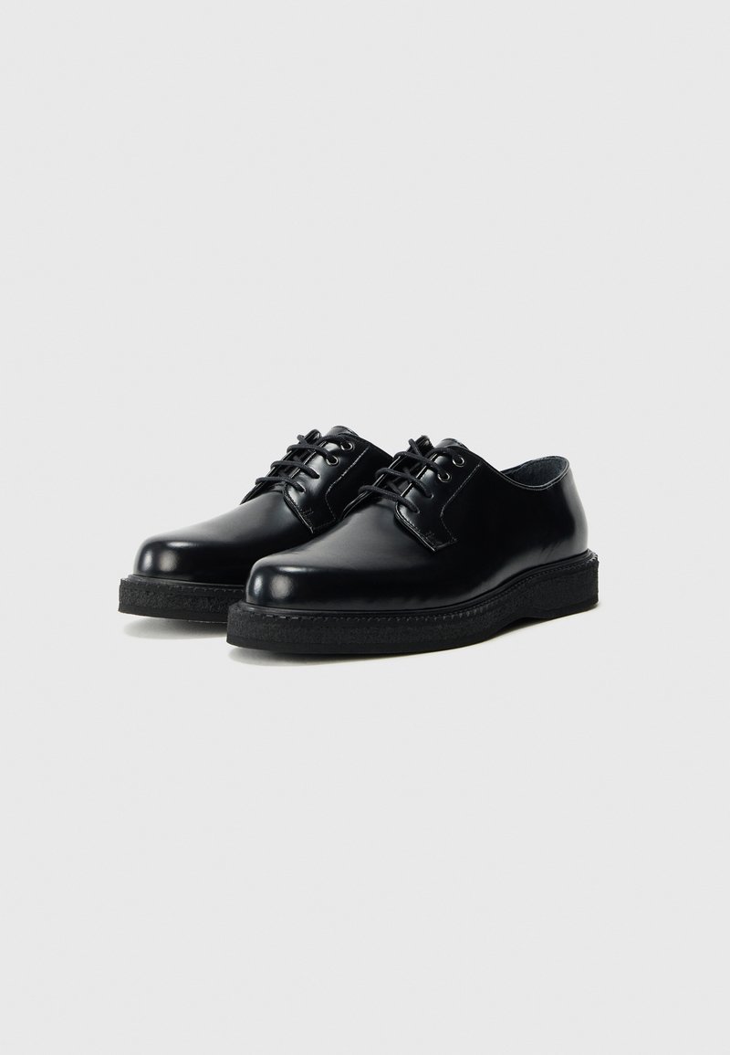 Black leather shoes with a smooth finish, rounded toe, and lace-up closure. Notable rubber sole with textured detailing.