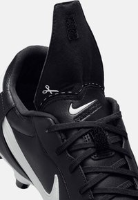 Crampons de football en cuir noir avec un swoosh blanc, supérieur texturé et une languette comportant un détail de ciseaux cousu au talon. Lacets noirs.