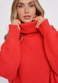 Czerwona sweterka z golfem o żeberkowanej teksturze, z długimi rękawami i luźnym krojem. Posiada wysoki kołnierz i miękką tkaninę.