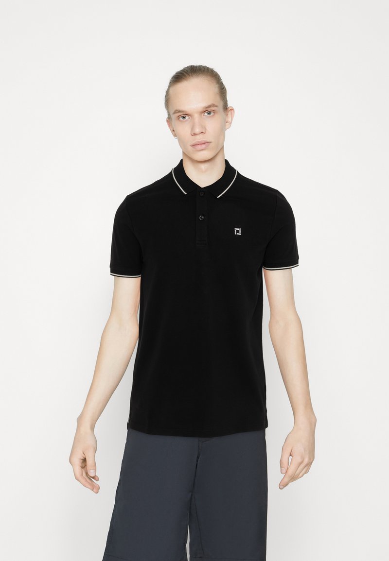 Zwarte polo met een kraag met witte bies en een knoopsluiting met drie knopen. Inclusief een klein logo op de linkerkant van de borst. Zacht materiaal.