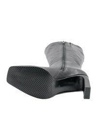 Botă din piele neagră, până la jumătatea gambei, cu fermoar, talpă texturată, vârf pătrat și toc bloc, văzută din lateralul talpii pe un fundal alb.
