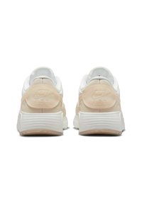 Baskets Nike avec une tige blanche, des accents pêche doux, un col rembourré et une semelle blanche texturée avec des rainures et un logo en relief sur le talon.