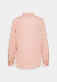 Chemise rose claire unie à manches longues avec col et poignets boutonnés, vue de dos sur fond blanc uni.