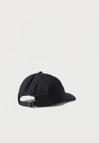 Μαύρο καπέλο μπέιζμπολ με ρυθμιζόμενο λουράκι και μεταλλικό κούμπωμα, που φαίνεται από πίσω σε λευκή απλή επιφάνεια.