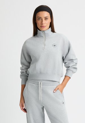Grå halvhøj lynlås sweatshirt med høj krave, ribbede manchetter og logo detaljer. Sammen med matchende grå sweatpants med sidelommer.