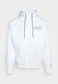 Bílá bunda Nike se zipem na přední straně, nastavitelnou kapucí a černými stahovacími tkaničkami. Na hrudi je logo a elastické manžety. Minimalistický design.