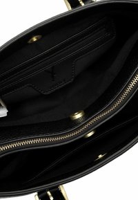 Wnętrze czarnej skórzanej torebki z wieloma przegródkami, złotym zamkiem błyskawicznym i magnetycznymi zatrzaskami.