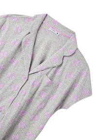 Maglietta grigia a maniche corte con motivo a fiocchi lilla pastello, dotata di colletto, patta con bottoni e una tasca sul petto.